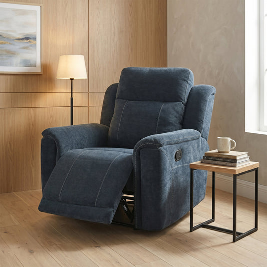 A blue upholstered recliner chair with a matching back cushion, shown in a staged living room setting with a wooden floor, side table, lamp, and wall art.