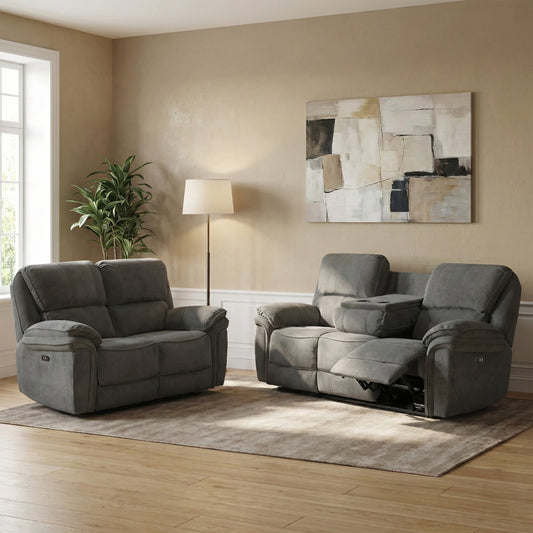 A gray reclining loveseat and matching gray reclining sofa placed in a living room with beige walls, a floor lamp, a window, a plant, and a large abstract wall painting.